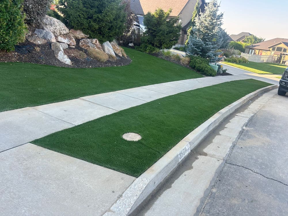 Artificial turf landscaping alongside a residential sidewalk and driveway.