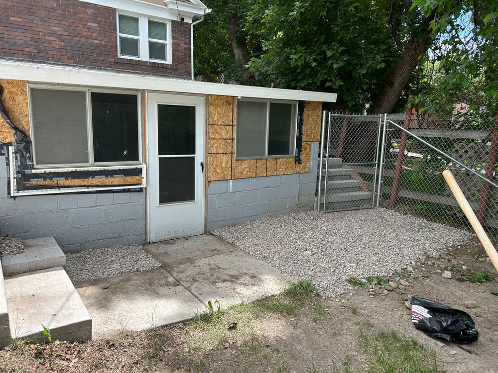Home renovation project with gravel patio and fenced area next to a partially finished home addition.