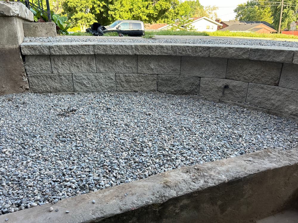 Gravel surface in a circular retaining wall outside a home on a sunny day.