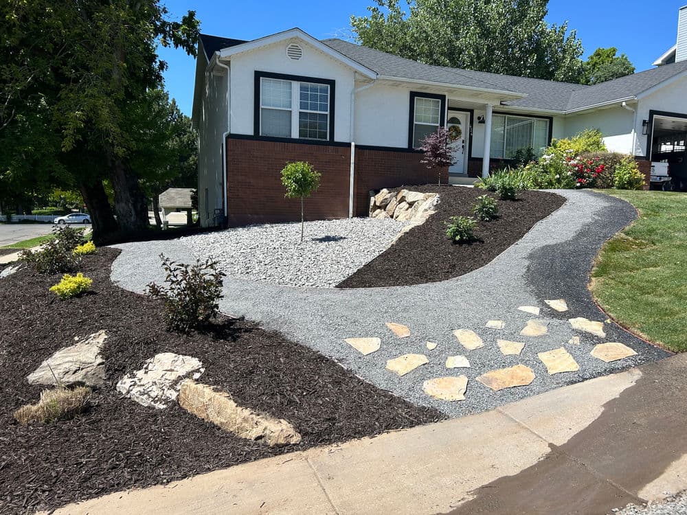 Landscaped front yard with gravel pathway, stone accents, and vibrant plants.