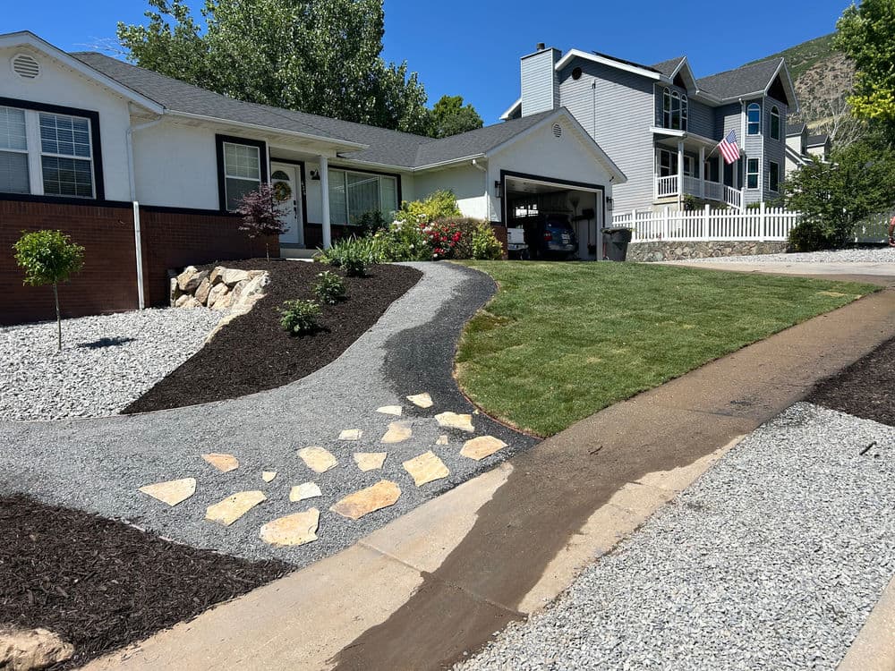 Landscape design with gravel, stone path, and manicured lawn in a residential neighborhood.